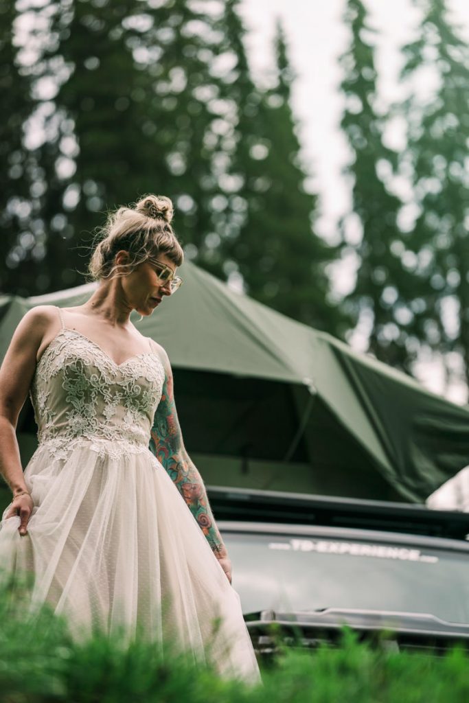 Die Braut tanzt vor dem Geländewagen.